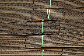 Stack of corrugated cardboard boxes tied with nylon rope and stacked in layers.