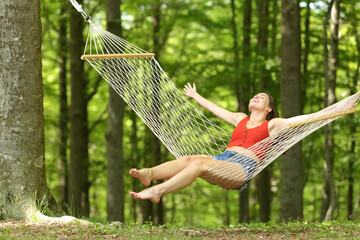 Excited woman swinging on hammock celebrating vacation