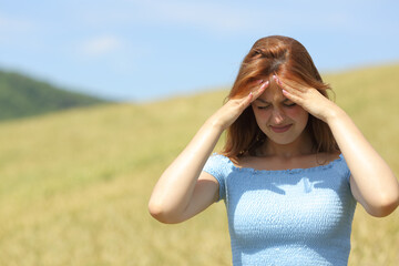 Woman suffering migraine in a field