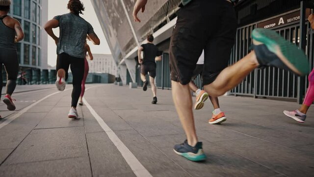 Progressive endurance athletes in portable shoes and clothing run through the city streets. Running club, a group of like-minded people, young women and men
