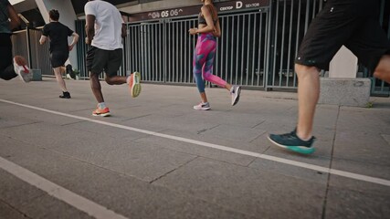 Back view of multiethnic team of men and women training running before marathon, active life. Running club, group of like-minded people run early in the morning at dawn along the urban streets