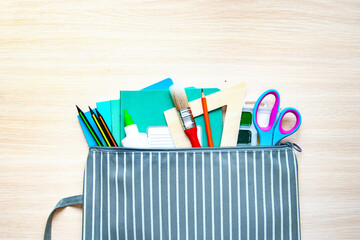The folder with different stationery on light background, flat lay with space for text. Back to school
