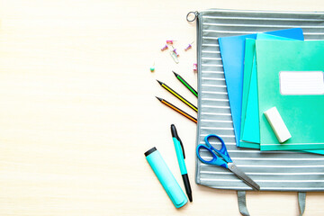 The folder with different stationery on light background, flat lay with space for text. Back to school
