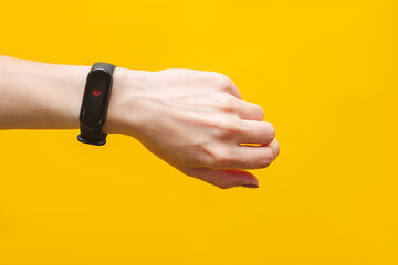 Smart watch with a heart rate monitor on a female hand isolated on a colored yellow background