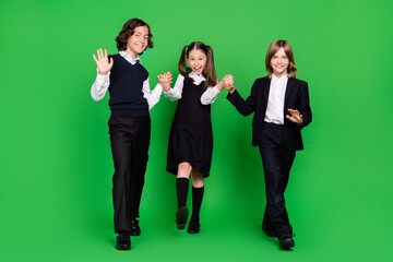 Full length photo of cool little girl boys hold hands go wave wear school uniform isolated on green background