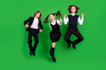 Full length photo of crazy small girl boys jump wear school uniform shoes isolated on green...