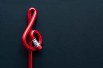 Red pen with treble clef form on black background