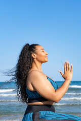 Fototapeta na wymiar Portrait young female relaxing practicing yoga with namaste on beach
