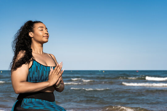 Beautiful woman practicing yoga ,tree pose with namaste on beach