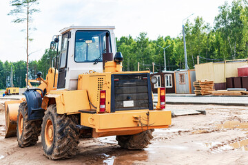 Heavy wheel loader with a bucket at a construction site. Equipment for earthworks, transportation and loading of bulk materials - earth, sand, crushed stone.