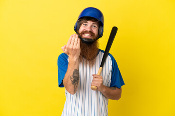 Redhead baseball player man with helmet and bat isolated on yellow background inviting to come with hand. Happy that you came