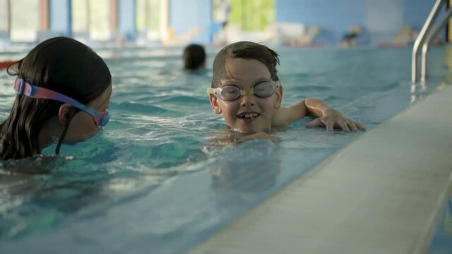 Happy children in swimming pool. Sports lifestyle concept. Boy and a girl in swimming lessons. - Powered by Adobe