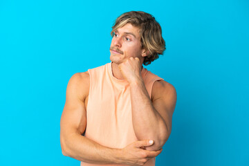 Handsome blonde man isolated on blue background with tired and bored expression