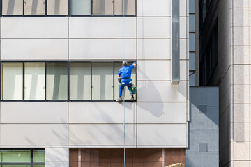 高層ビルの窓ガラスを磨く清掃員