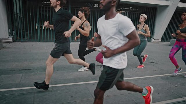 Black man and his team of athletes running through the stadium. African American man and his like-minded friends dressed in a portable uniform have a group running training