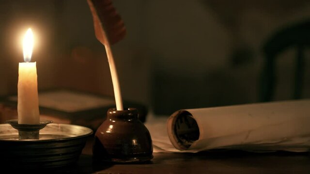 relaxing scene lit by an beeswax candle of a 18th century desk with scroll and quill pen