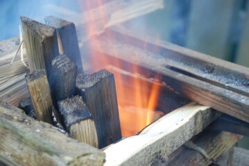 A pine fire is kindled. Several logs of wood are stacked in a square tower for a fire in the middle of the tower, flames and smoke are emitted.