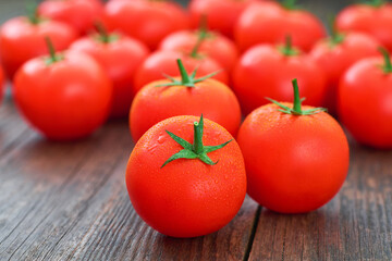 fresh red tomatoes and water drops on a wooden table.