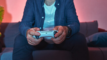 Closeup image of a man gamer player holding gamepad controller playing video game sitting alone on...
