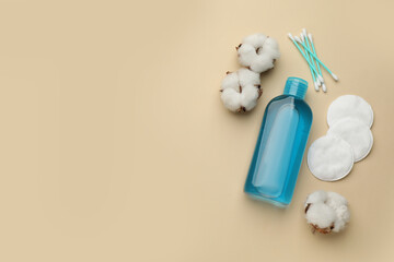 Cotton pads, swabs, flowers and makeup removal product on beige background, flat lay. Space for text