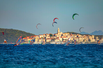 Tourists windsurf and kitesurf in heart of beautiful Dalmatia on sunny evening.