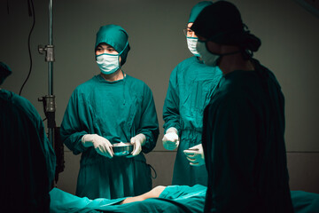 Asian Medical Team Performing Surgical Operation in Modern Operating Room. Doctors and Nurse in green uniform concentrate working in the hospital