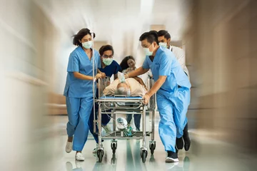 Fotobehang Emergency Department: Group of Doctors, Nurses, Paramedics Push Gurney, Stretcher with Seriously trauma Patient towards the Operating Room. Group of Asian staff rushing to save in the hospital © butsaya33