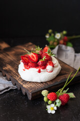 dessert Anna Pavlova. Meringue with whipped cream and strawberries on a dark background