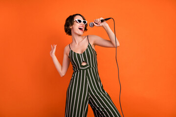 Photo of young attractive girl happy positive smile singer star music lover isolated over orange color background