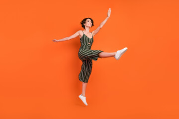 Full size profile side photo of young excited girl happy positive smile acrobatics isolated over orange color background