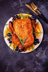 Fried chicken with rosemary and garnish served on a white plate.