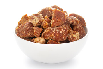 Close-Up of sugarcane jaggery piece in white ceramic bowl over white background