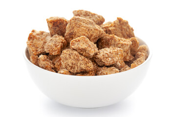 Close-Up of sugarcane jaggery piece in white ceramic bowl over white background