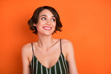 Photo of young cheerful girl happy positive smile curious interested look empty space isolated over orange color background