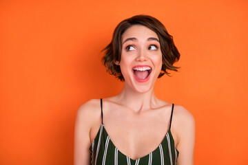 Photo of young girl happy positive smile amazed excited curious look empty space isolated over orange color background