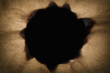 Vintage paper with a burned round hole in the middle with black background. Copy space. Magic and wizardry concept.
