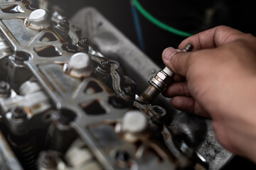 Old Car spark plug in a hand of Technician remove and change in engine room blur background service...
