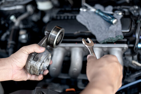 Wrench in the hand of a technician for take off Belt Tension Pulley old part car engine Replacement of spare parts in engine room