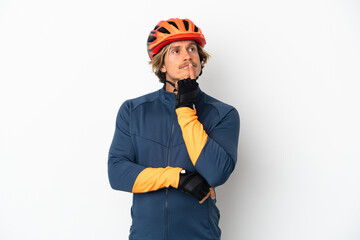 Young blonde cyclist man isolated on white background having doubts while looking up