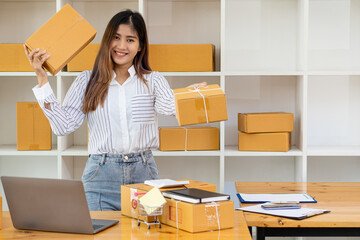 Small business entrepreneur, SME, independent, young Asian woman with box and laptop in small business owner's office in Asia. online marketing packing box delivery SME e-commerce success concept