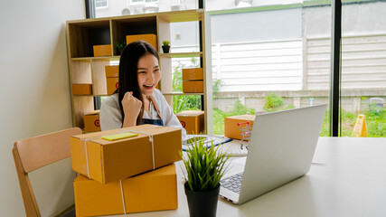 Small business entrepreneur, SME, independent, young Asian woman with box and laptop in small business owner's office in Asia. online marketing packing box delivery SME e-commerce success concept