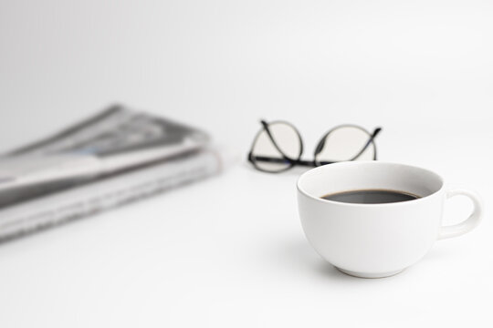 White coffee cup,glasses,News paper on the white table