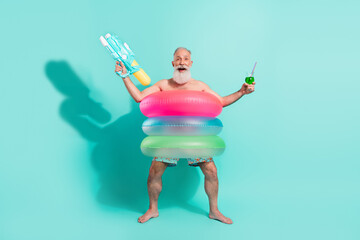 Photo of sweet excited pensioner shirtless standing inside floated circles drinking alcohol shooting gun isolated teal color background