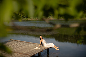 Relaxing young woman on wooden pier at the lake