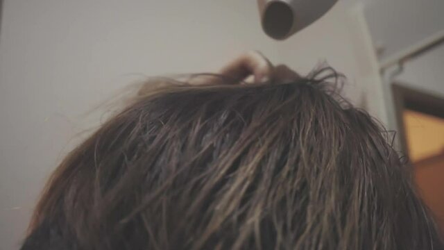 Woman drying her hair with a hair dryer.