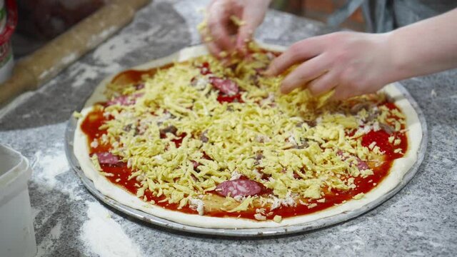 Pizza making process. Sprinkle with grated cheese.