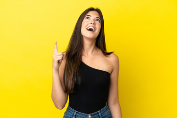 Young Brazilian woman isolated on yellow background pointing up and surprised
