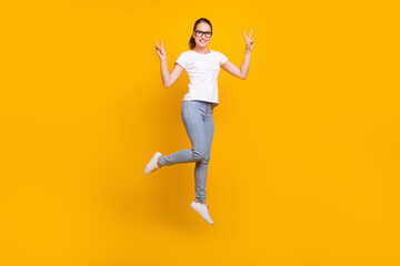 Fototapeta na wymiar Full length photo of happy enjoy positive woman jump up make v-signs isolated on yellow color background