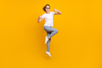 Fototapeta na wymiar Full length photo of funky happy positive woman make thumbs up jump wear jeans isolated on yellow color background