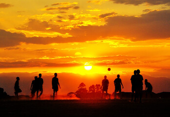 Fototapeta premium Silhouettes of unrecognizable children playing soccer at sunset